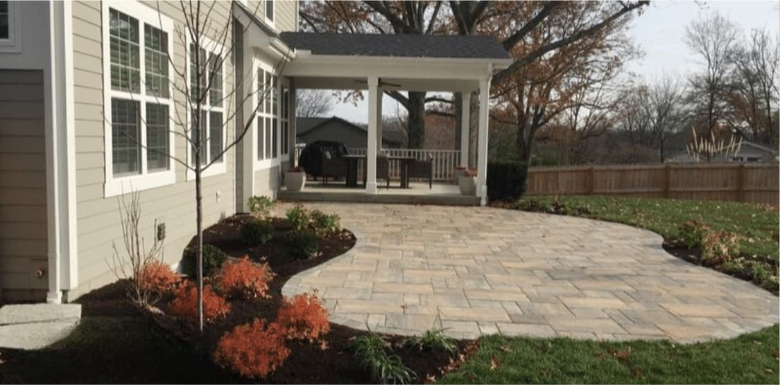 Finished curved paver patio with planted borders beneath the covered porch